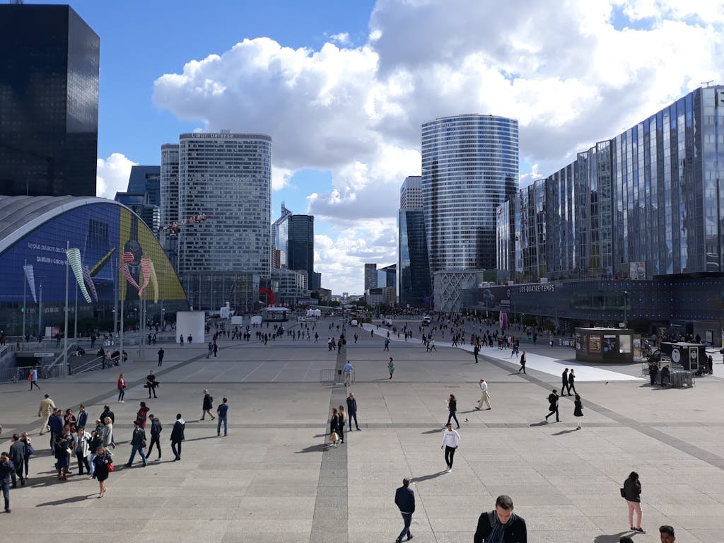 A vibrant scene of La Défense in Paris with modern architecture and a lively crowd.
