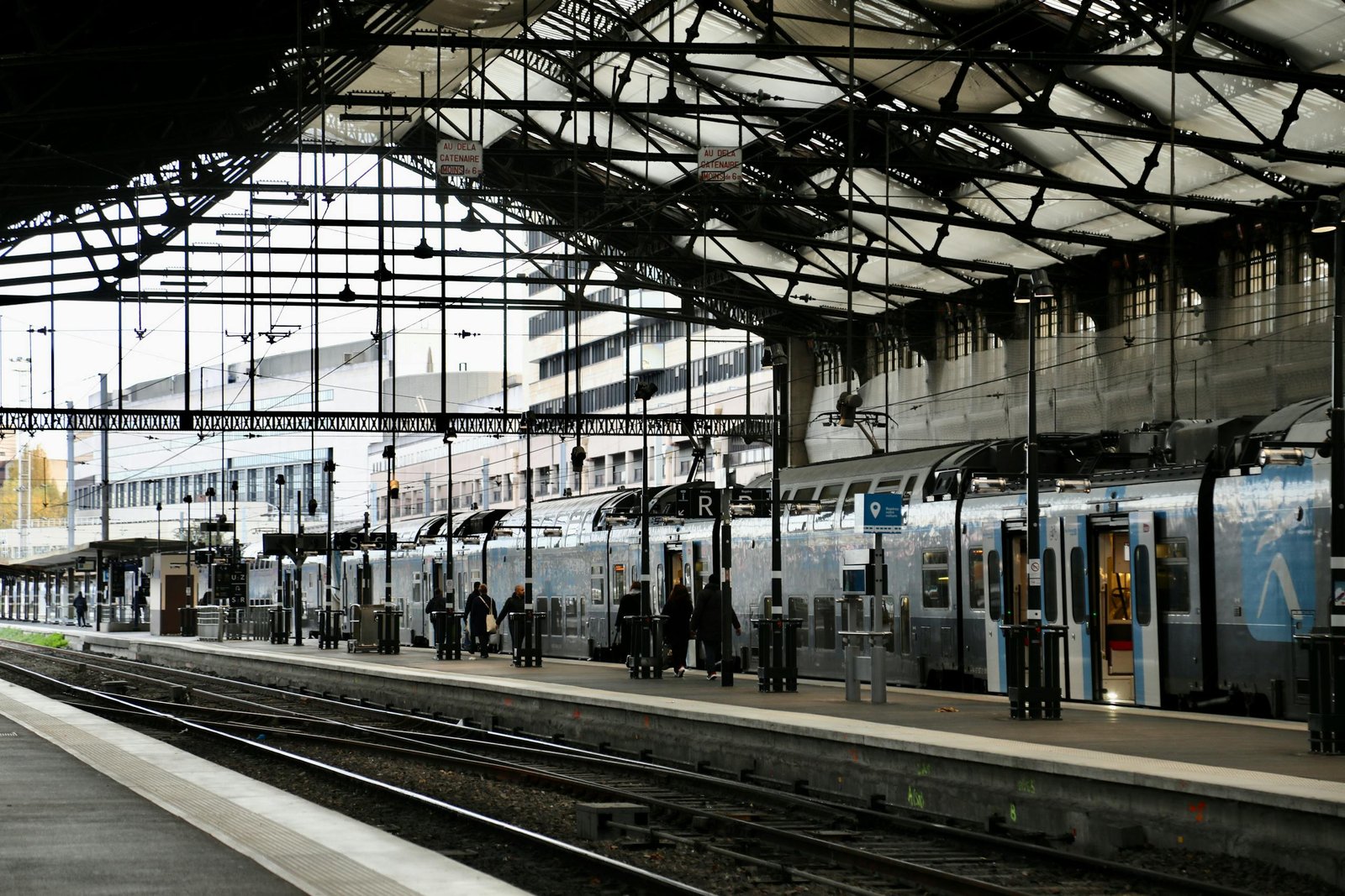 Train station in Paris, France, with people boarding trains. Urban transit scene.