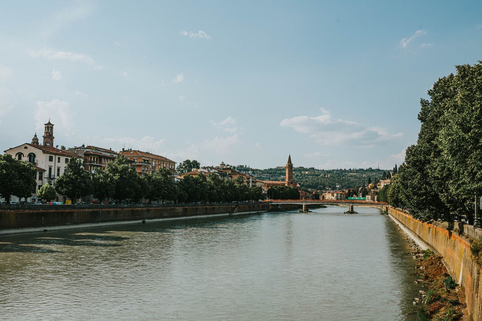 Vista del río Adige a su paso por Verona, con puentes emblemáticos y edificios históricos bajo un cielo despejado